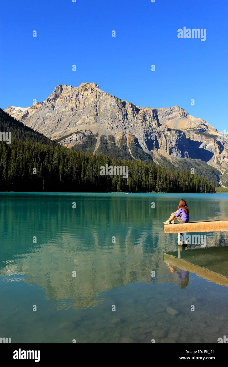 Giovane donna seduta su un molo presso il Lago di Smeraldo, Parco Nazionale di Yoho, British Columbia, Canada Foto Stock