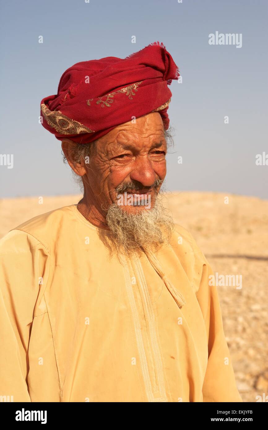 Un Omani non identificato agricoltore indossando un muzzar (tradizionale turbante di lana) indagini del suo paese nel deserto interno di Oman. Foto Stock