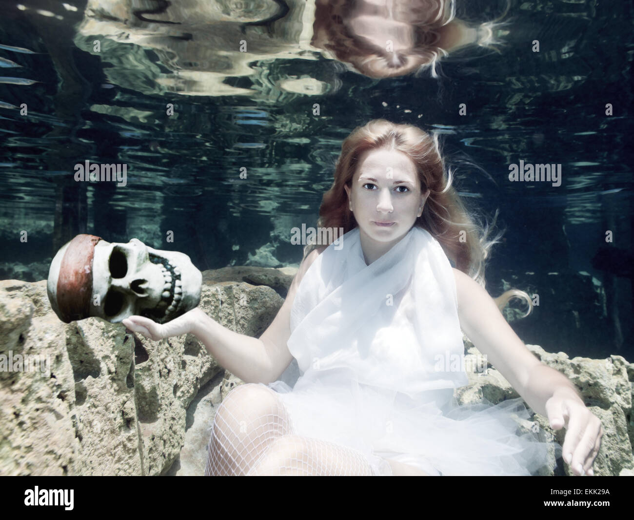 Donna con il cranio in abito bianco underwater Foto Stock