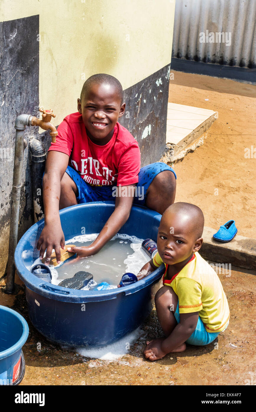 Johannesburg Sud Africa,Soweto,ragazzi maschi neri bambini bambini fratelli,lavaggio,vasca,acqua di rubinetto,esterno,SAfri150307072 Foto Stock