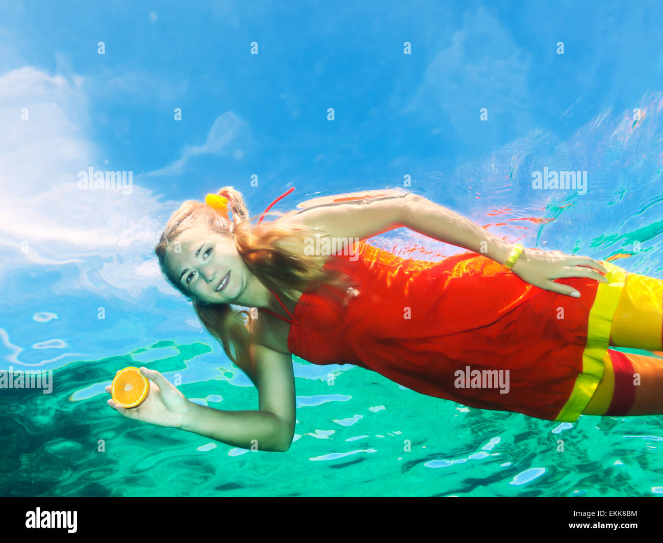 Riprese subacquee di una donna divertente con arancia Foto Stock