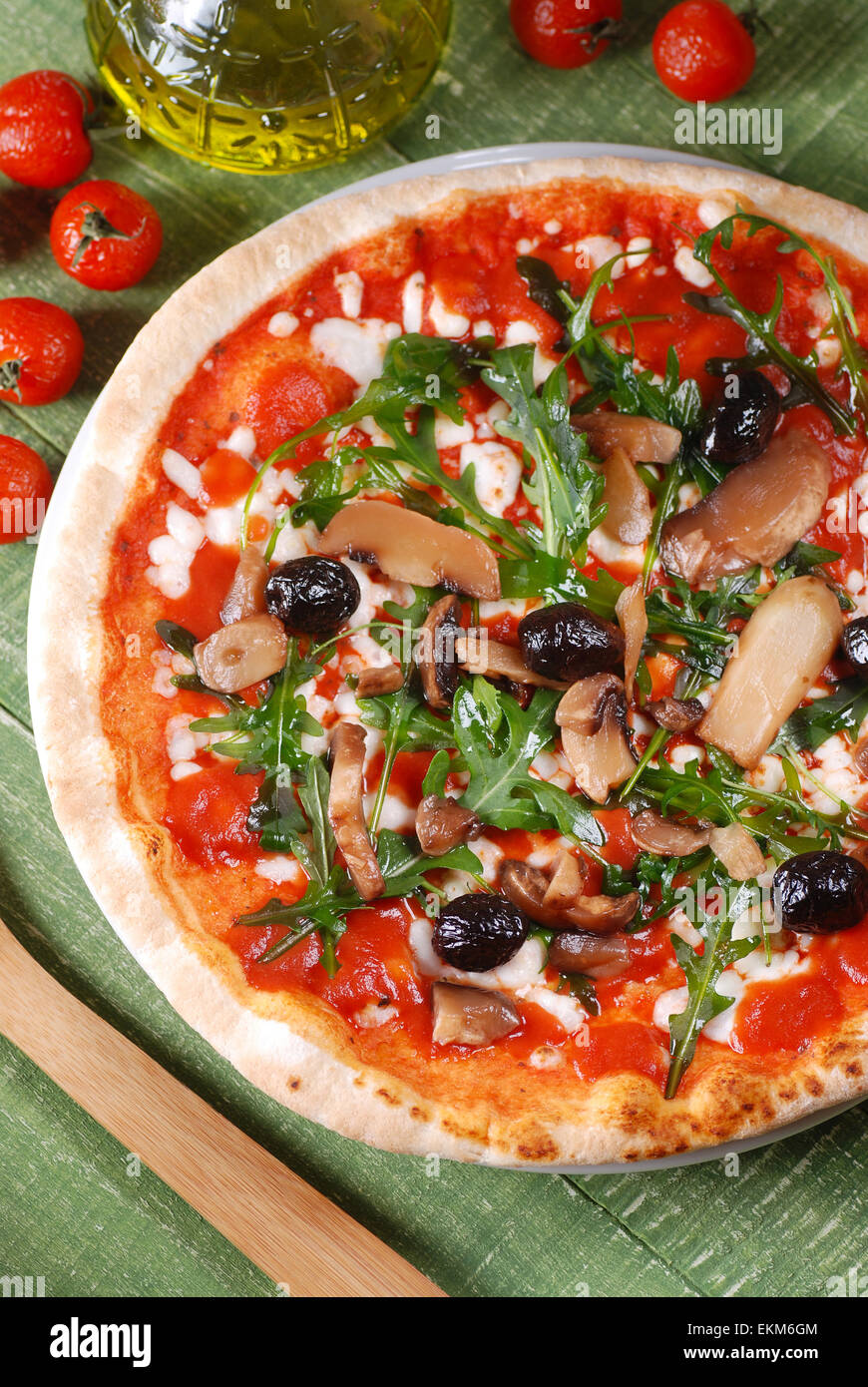 La pizza italiana con rucola e funghi sul tavolo verde Foto Stock