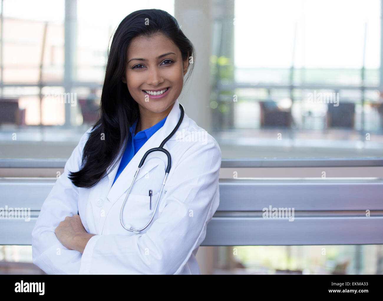 Closeup ritratto di cordiale e sorridente fiducioso medico donna, professionisti sanitari con labcoat stetoscopio e braccia incrociate Foto Stock