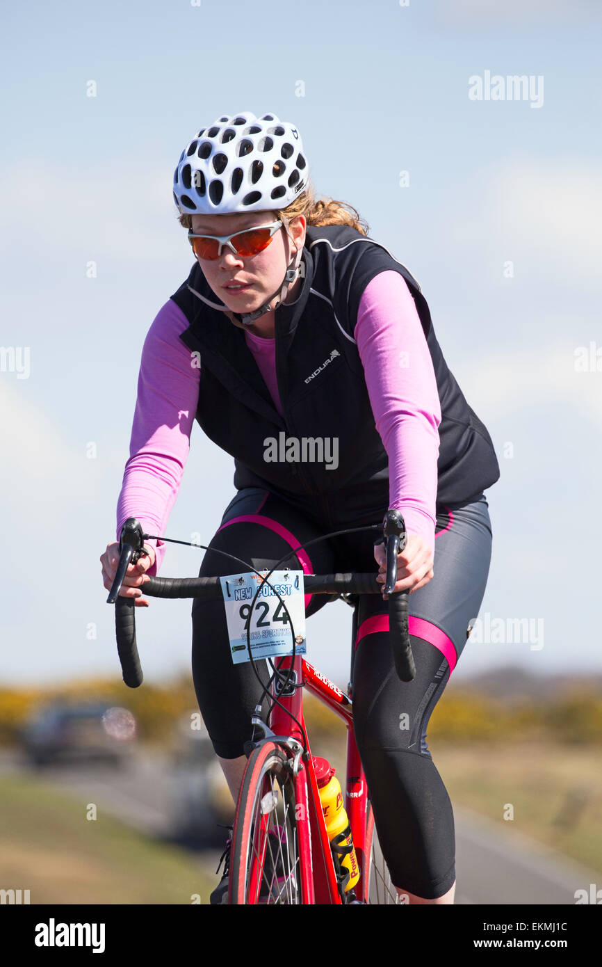 Una femmina di ciclista compete nella nuova foresta dimenare evento sportivo su una soleggiata domenica di primavera Foto Stock