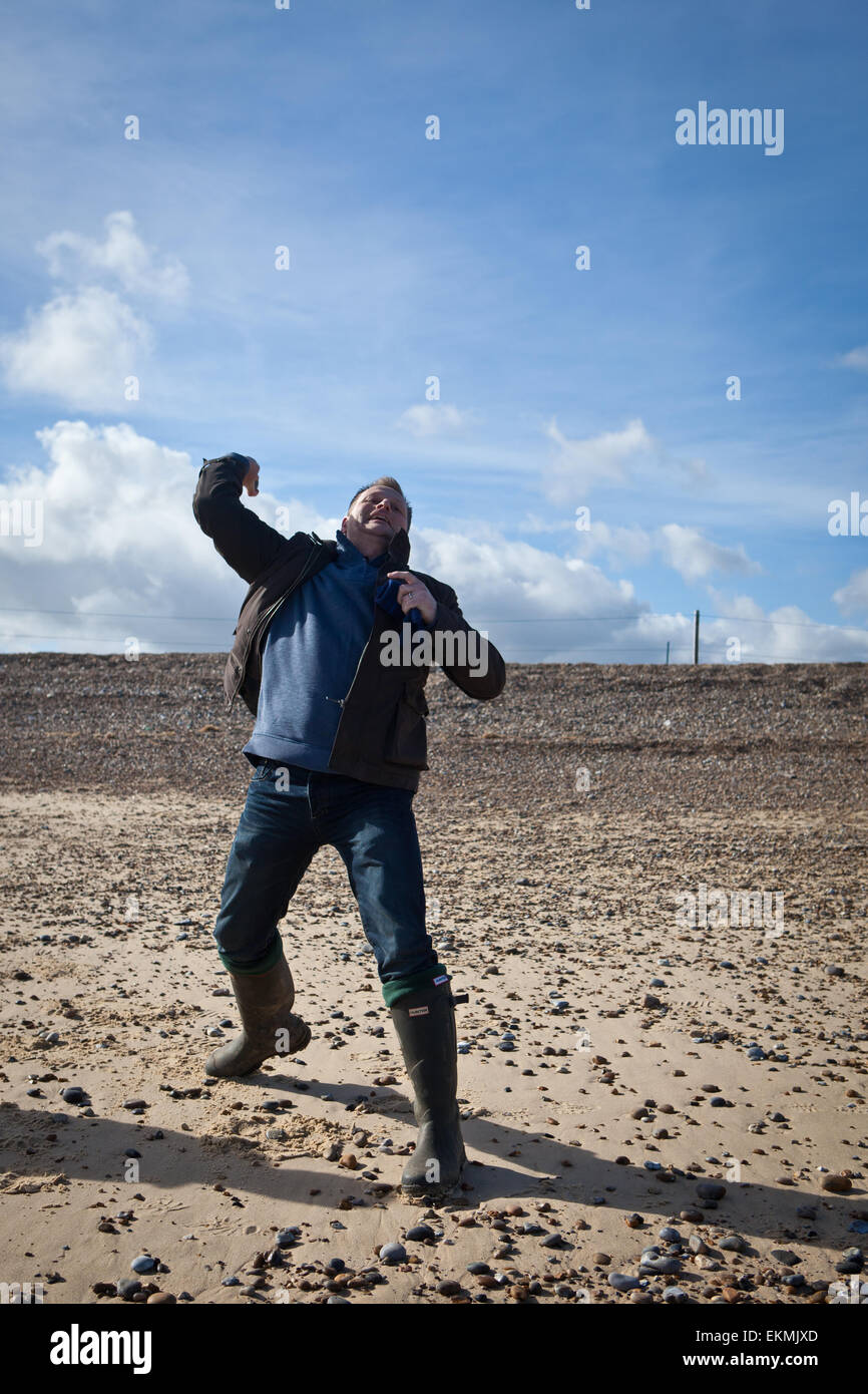 L'uomo gettando da ciottoli Dunwich Heath e spiaggia, Suffolk Foto Stock