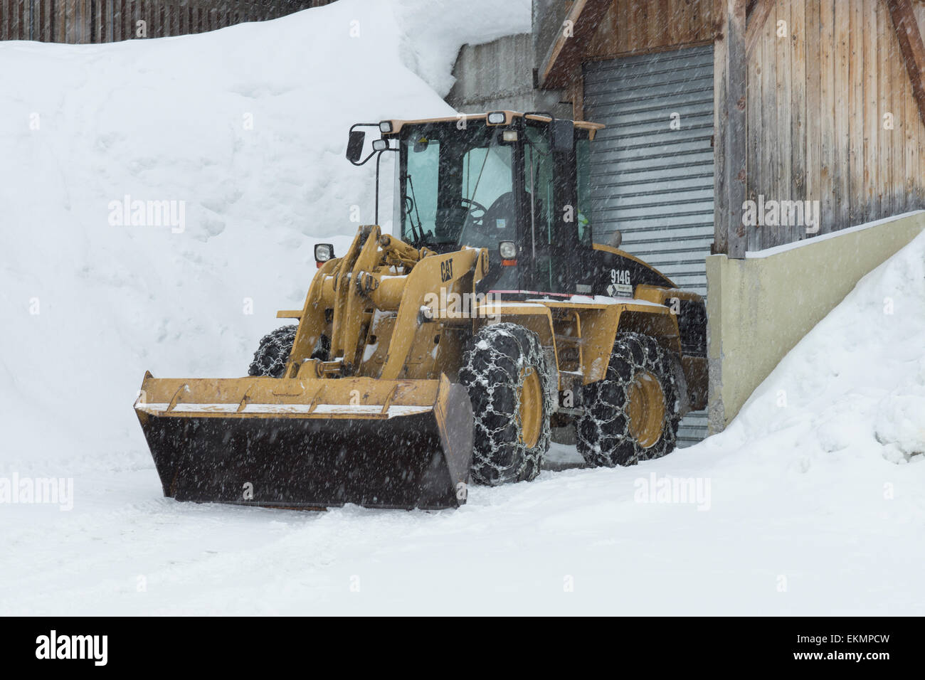 Giallo JCB Digger tempesta di neve parcheggiato ruota per catena Foto Stock