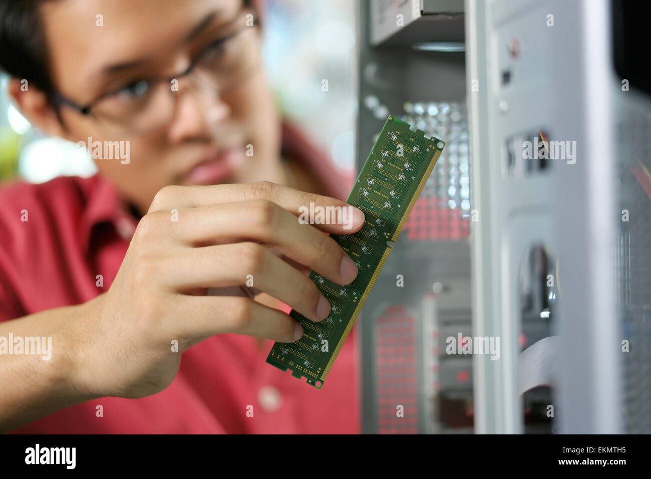 Giovani asiatici proprietario di un negozio di lavorare nel negozio di computer riparazione di computer e di aggiungere RAM al pc. Focus sulla mano che tiene banco di RAM Foto Stock
