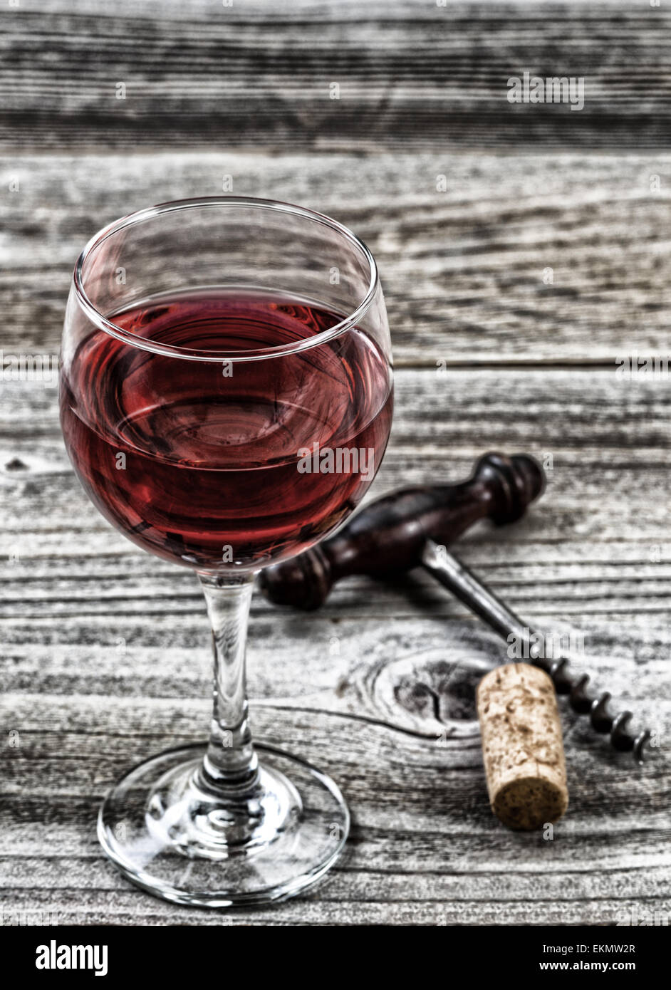 Concetto Vintage vino, concentrarsi sul labbro anteriore del vetro, con antichi cavatappi e sughero in background su legno rustico. Foto Stock