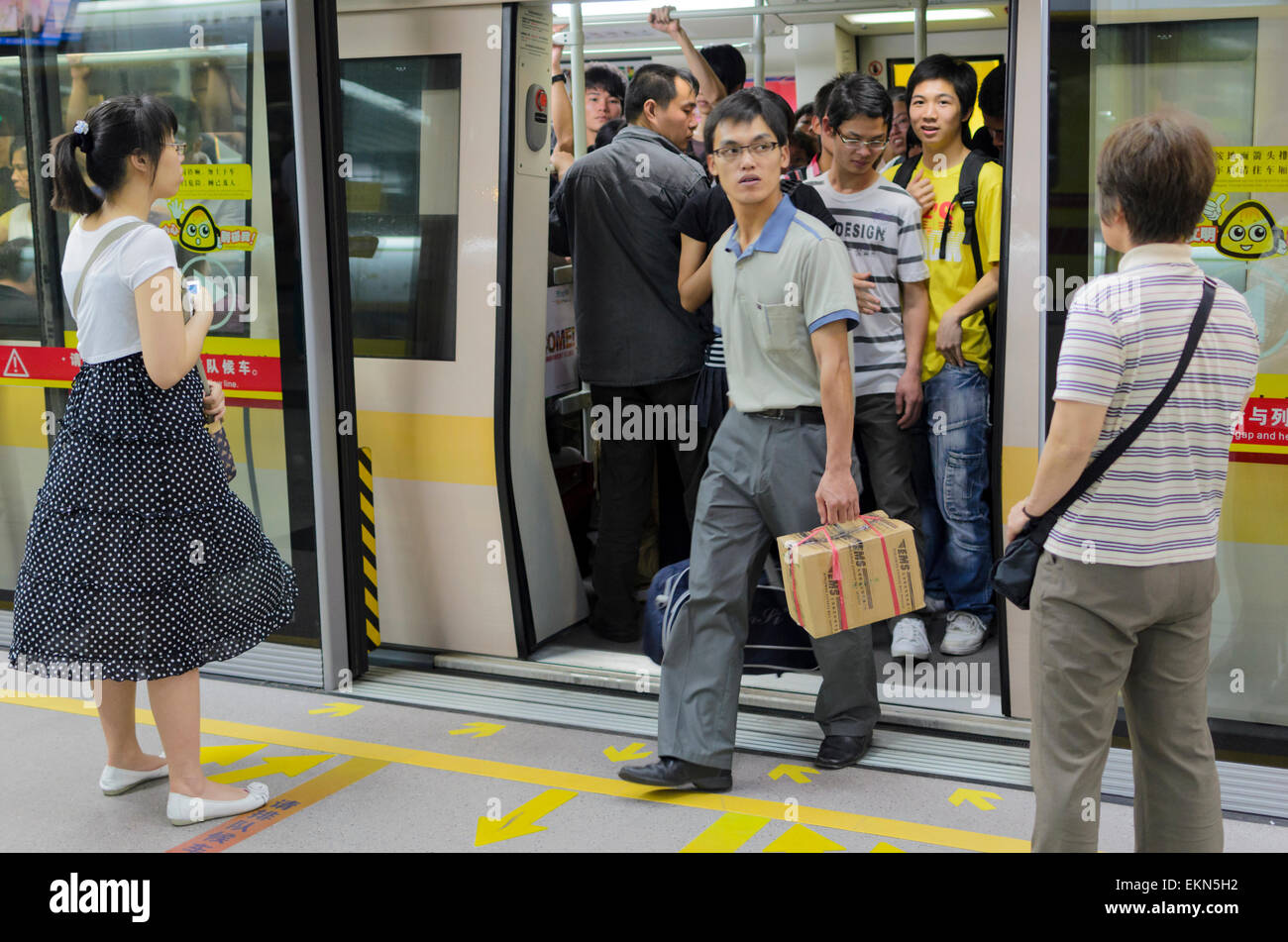 Passeggeri scendere un treno della metropolitana di Guangzhou, Cina. Le porte dello schermo può essere chiaramente visto tra la piattaforma treno porte. I mezzi di trasporto pubblici; alla metropolitana Foto Stock