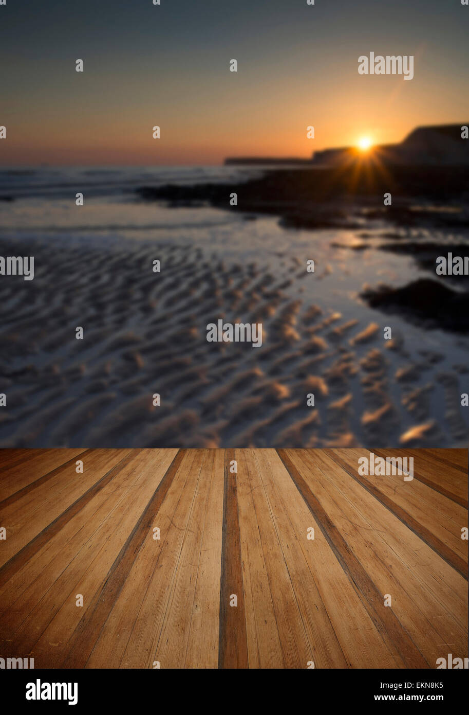 Immagine di panorama della spiaggia rocciosa al tramonto con una lunga esposizione motion blur mare con doghe in legno piano Foto Stock