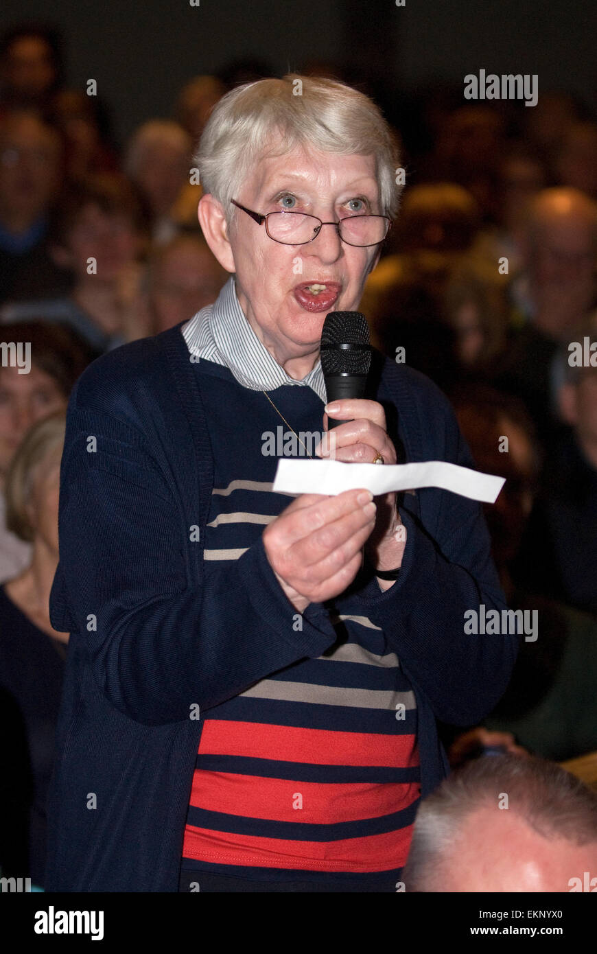 Donna anziana che pongono una questione ad un pannello di politici a un evento hustings prima delle elezioni generali britanniche il 7 maggio 2015... Foto Stock