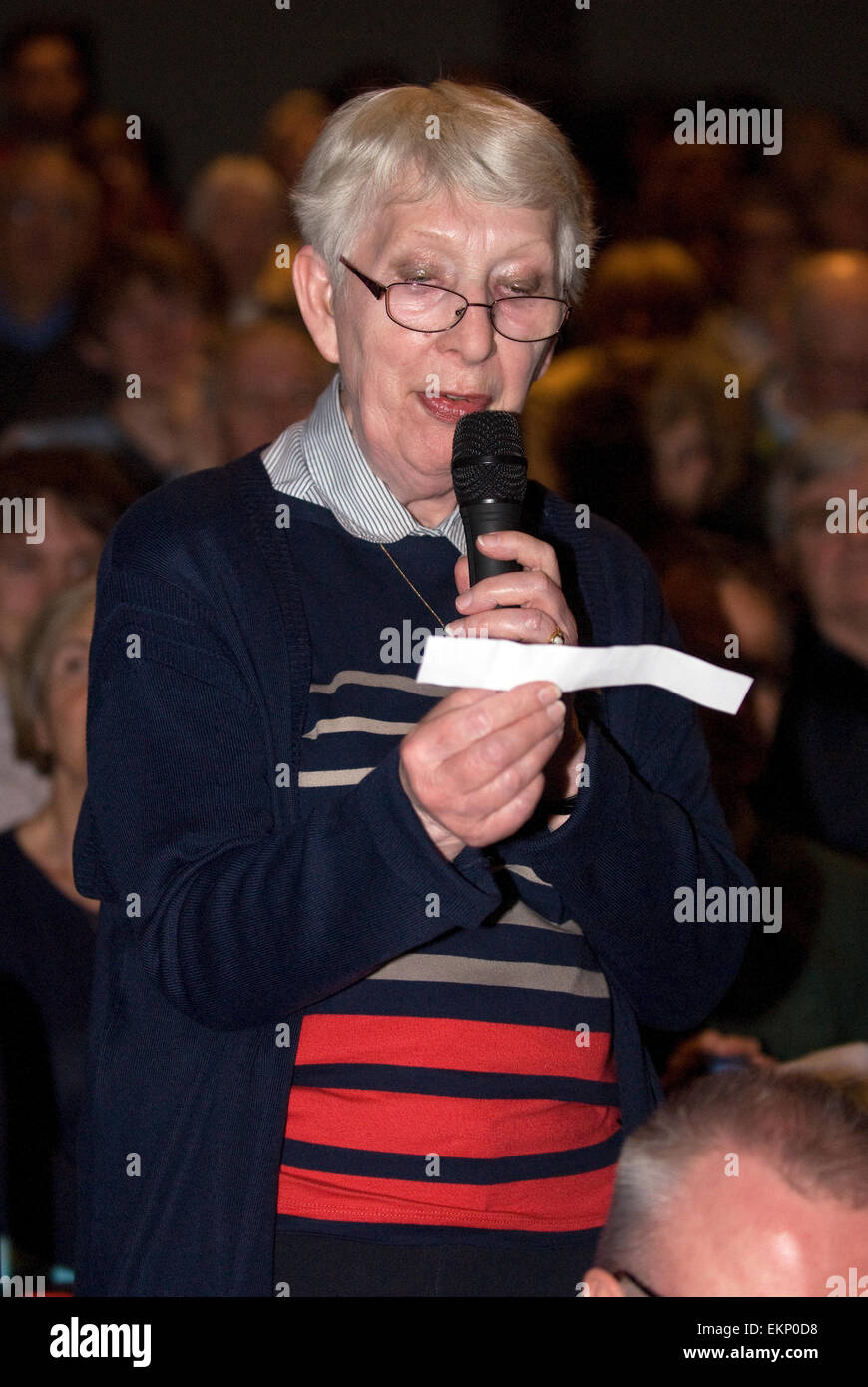 Donna anziana che pongono una questione ad un pannello di politici a un evento hustings prima delle elezioni generali britanniche il 7 maggio 2015, Fa Foto Stock