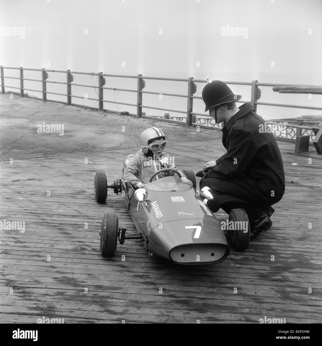 Otto anni di Thomas Barnard nella sua auto racing, che parla di un poliziotto sul Molo Ovest di Brighton davanti al british giocattolo auto e ciclo Rally presso il British Toy Fair in apertura di giornata. Il 28 gennaio 1968. Foto Stock