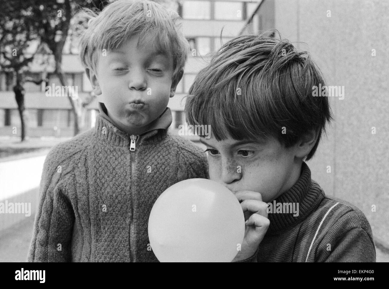 Otto anni di Joseph Clifford di Hackney soffia il suo palloncino come il suo fratello minore Paolo, di età compresa tra i 5, aiuta soffiando un immaginario uno. 1 settembre 1970. Foto Stock