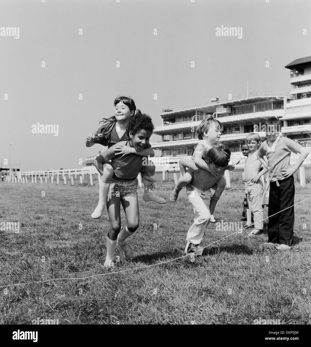 Bambini che portano i loro partner sulle loro spalle durante un cavallo e stile jockey uovo e cucchiaio gara sulle Downs presso la Epsom dove gli allenatori dei bambini hanno avuto una vacanza lontano dal Peckham. La giornata è stata organizzata dalla Peckham insediamento. Il 16 agosto 1973. Foto Stock