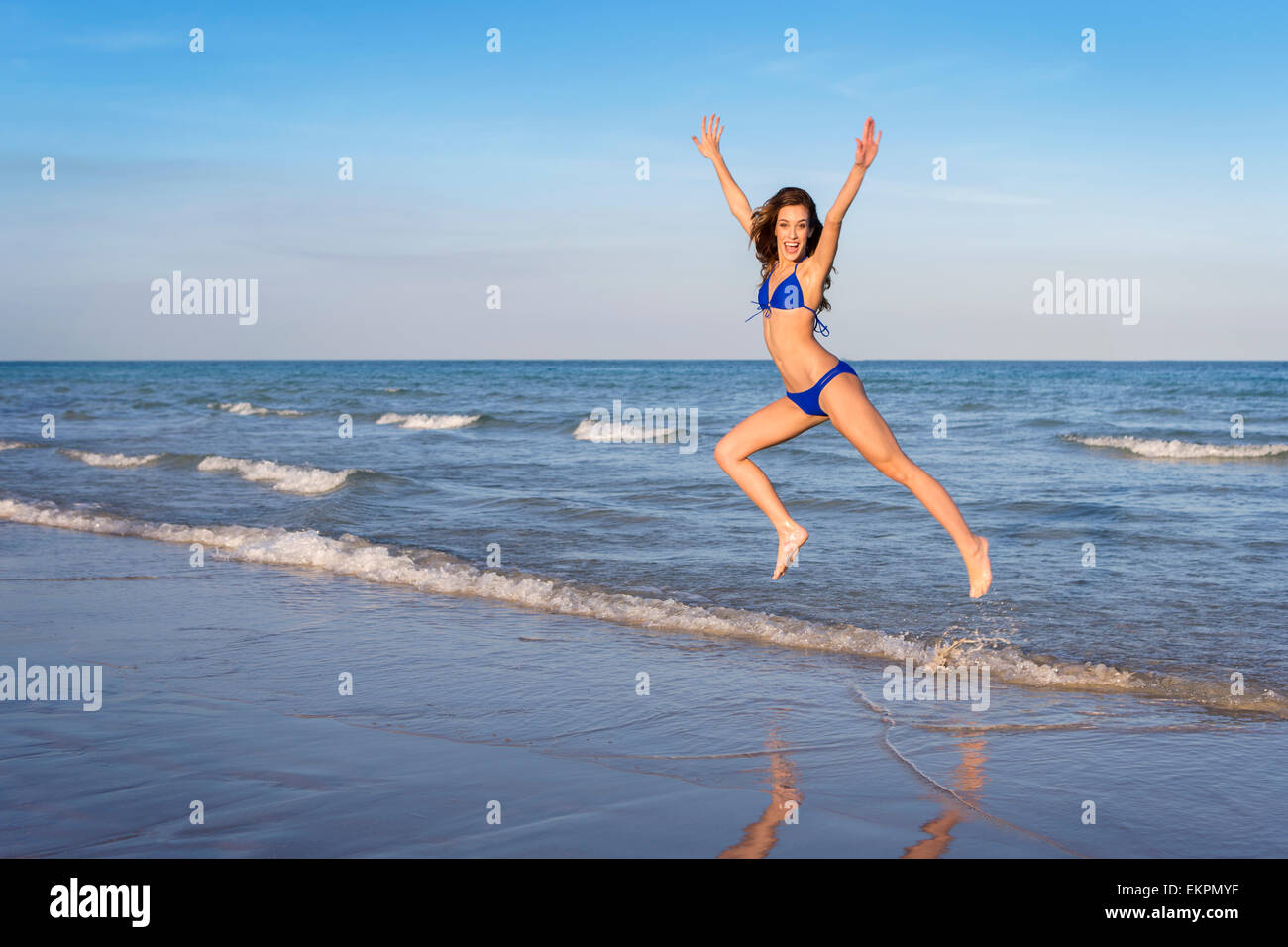 Giovane donna allegra in bikini salto sulla spiaggia. Foto Stock