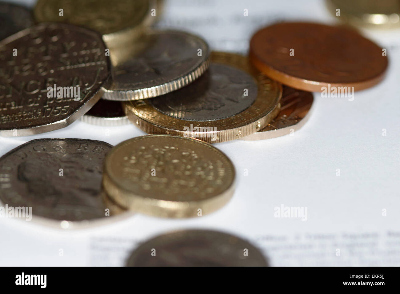 Pila di monete del regno unito di varie denominazioni sul foglio di carta Foto Stock