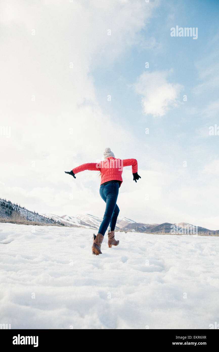 Una ragazza con gambe lunghe che corrono sulla neve. Foto Stock