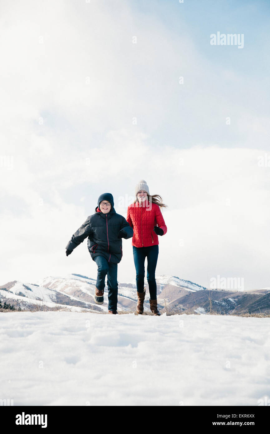 Due bambini, fratello e sorella che corrono sulla neve. Foto Stock