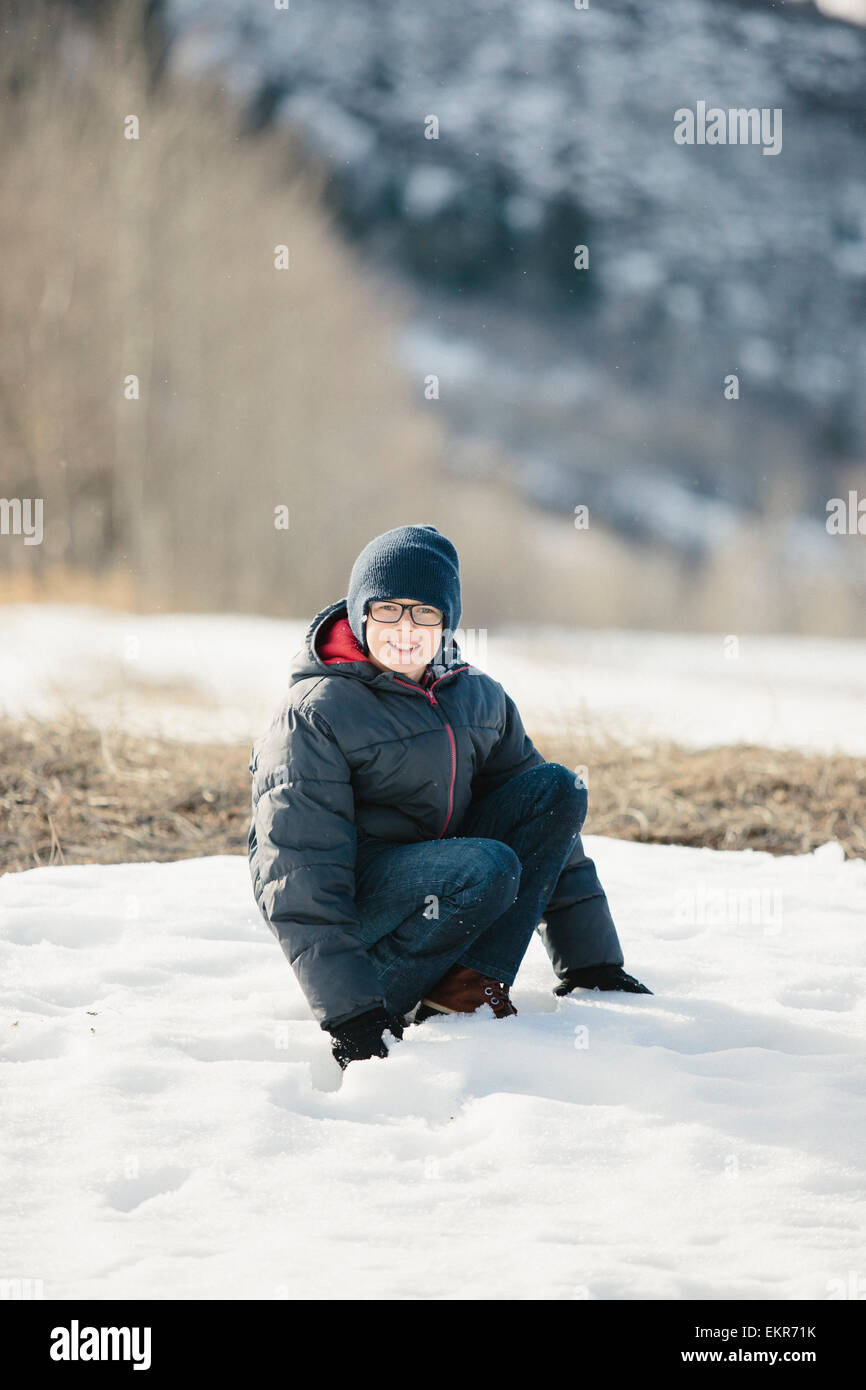 Un ragazzo in un mantello blu e cappellino nella neve. Foto Stock