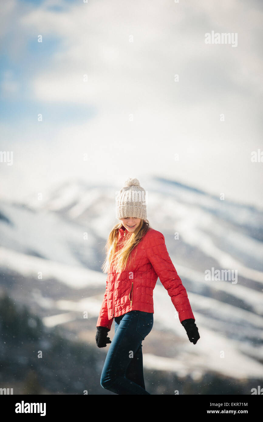 Una giovane ragazza in un cappotto rosso e cappellino all'aperto d'inverno. Foto Stock