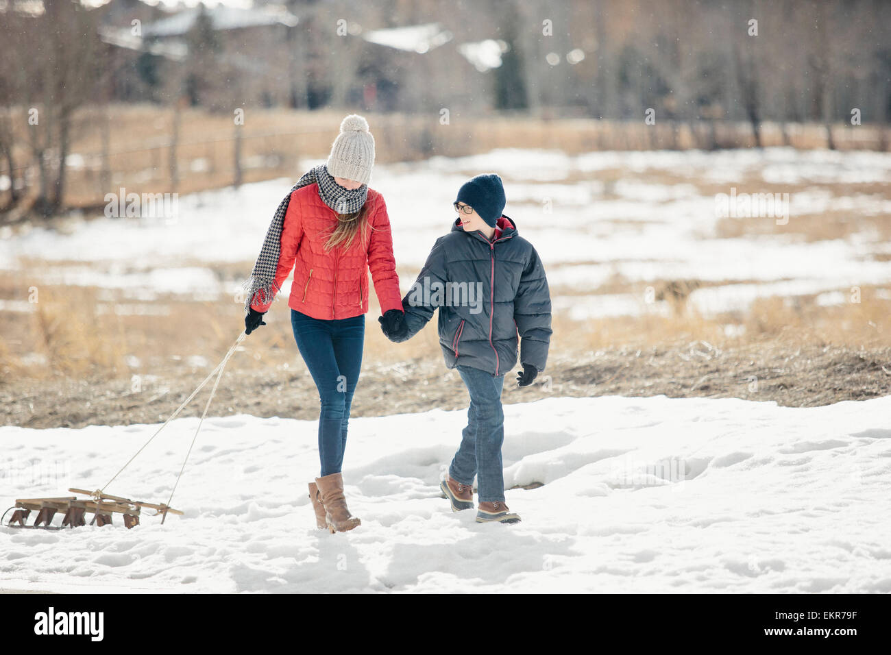 Un fratello e una sorella nella neve, uno tirando una slitta. Foto Stock