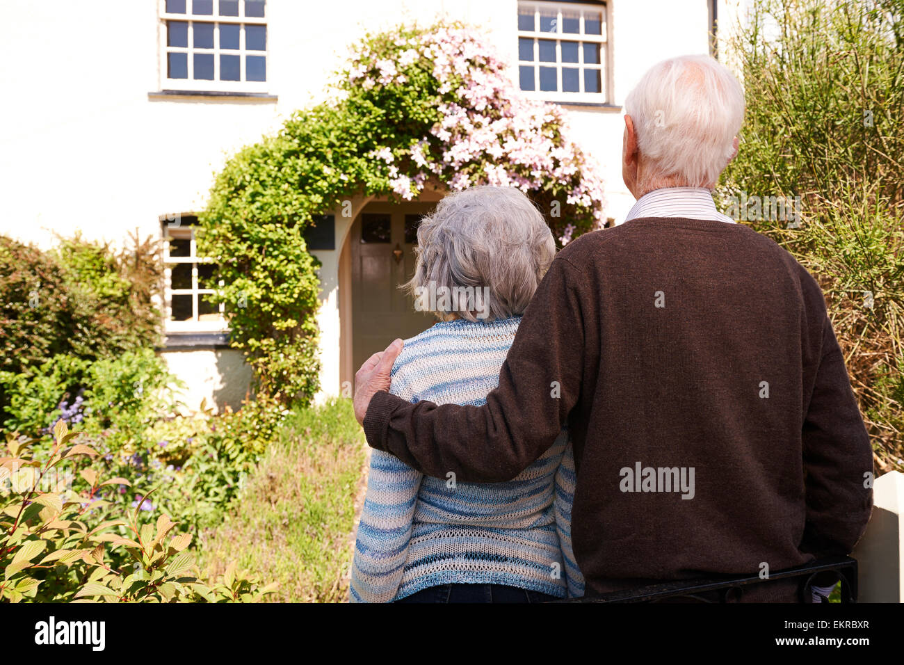 Vista posteriore della coppia Senior al di fuori del grazioso cottage Foto Stock