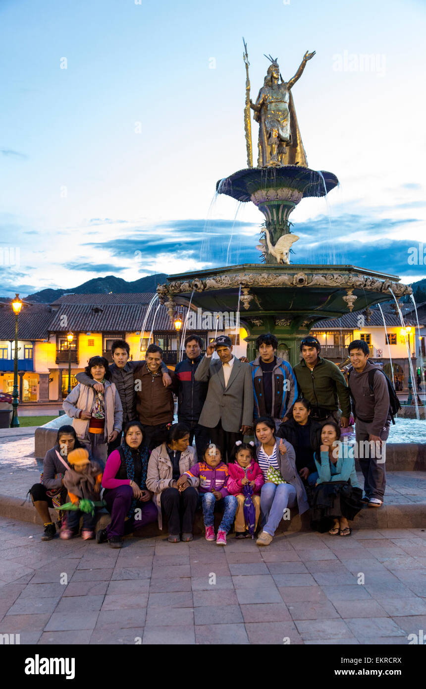 Perù Cusco. I peruviani che posano per una foto di gruppo sotto la statua del re inca Pachacutec sopra Fontana in Plaza de Armas. Foto Stock