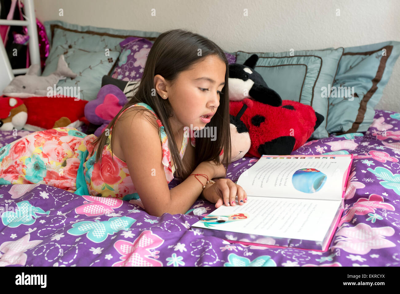 Bimba di 8 anni, la lettura di una storia sul suo letto a casa. Foto Stock