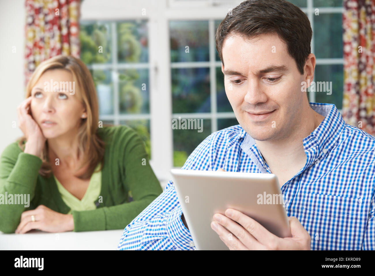 Infelice donna seduta a tavola come Partner utilizza tavoletta digitale Foto Stock