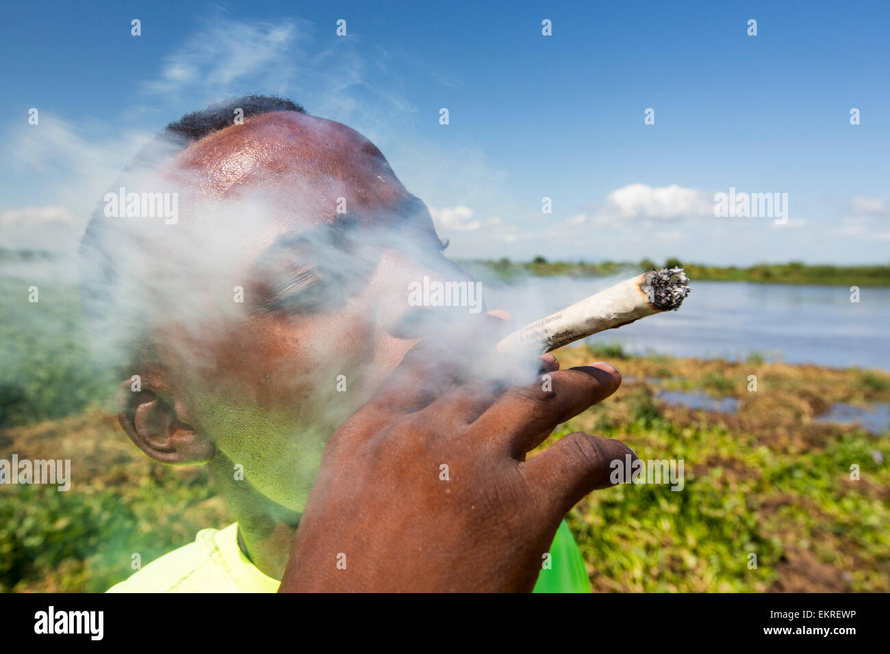Un uomo di fumare coltivati localmente la cannabis in un rotolo spliff, Nsanje, Malawi. Foto Stock