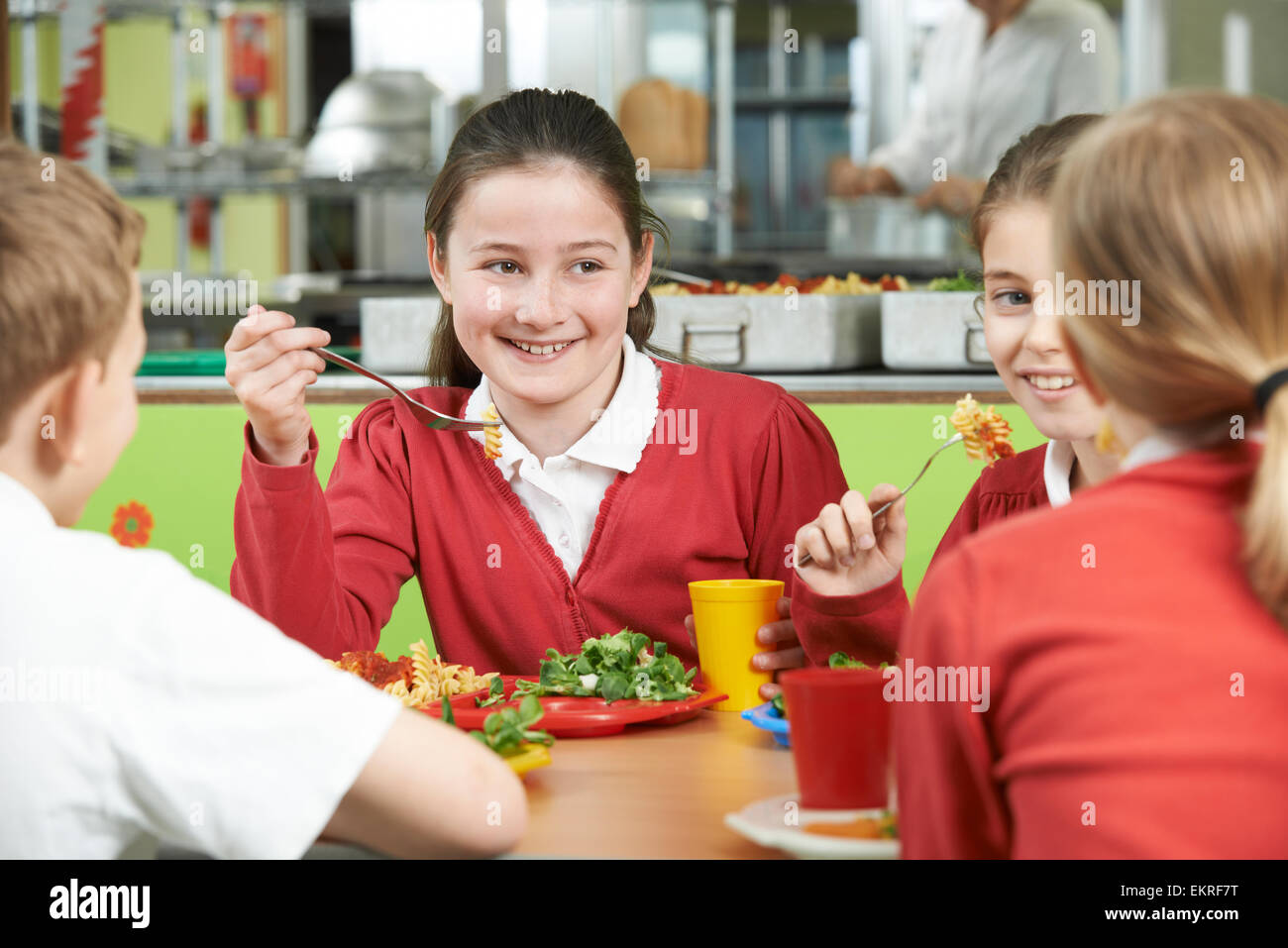 Gruppo di studenti seduti al tavolo in mensa scolastica di mangiare il pranzo Foto Stock