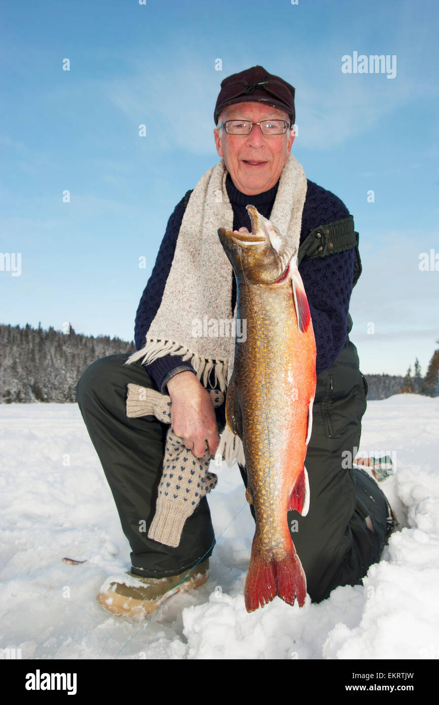 Ice fisherman tenendo un grande pesce splake; Ontario, Canada Foto Stock