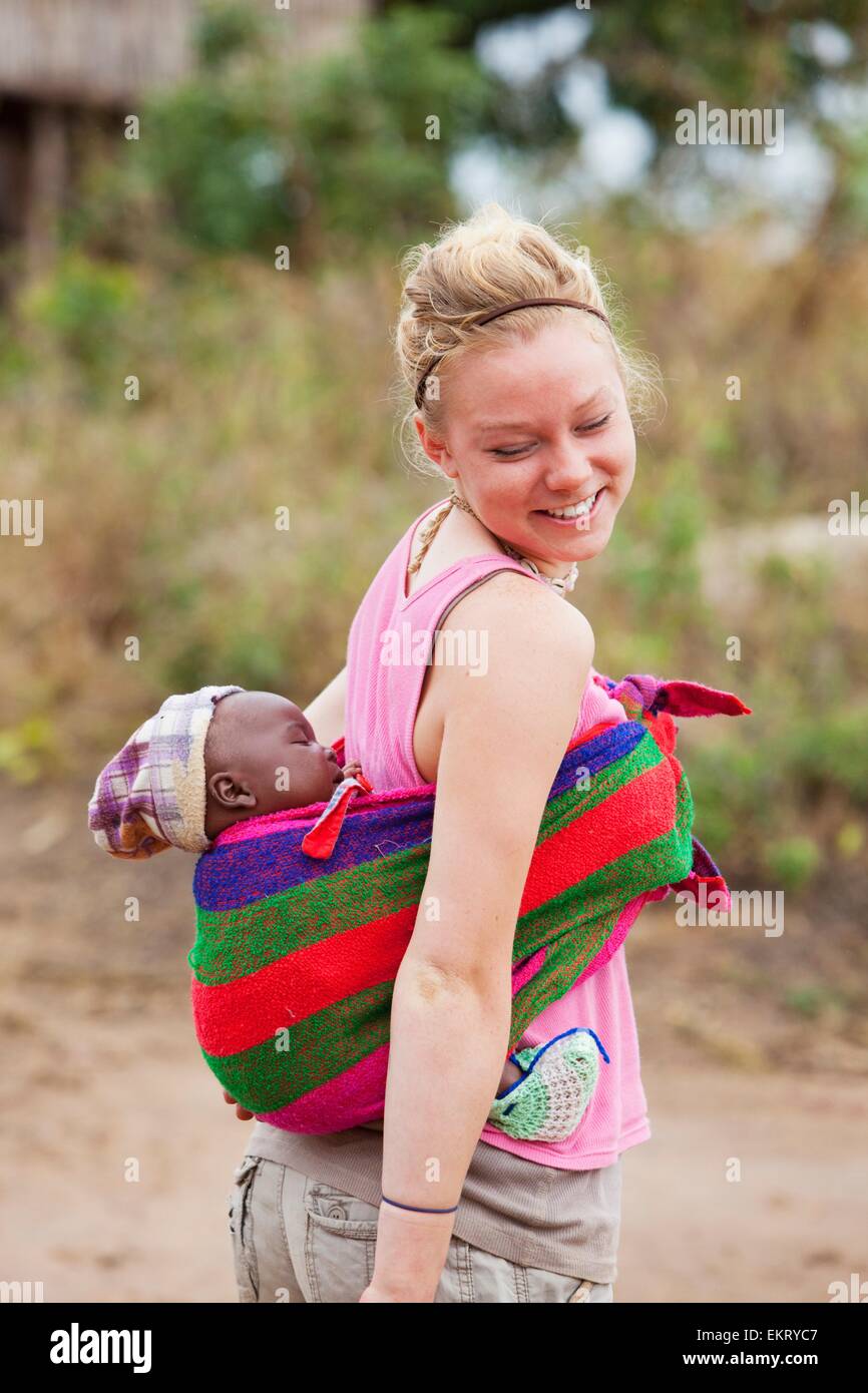 Una giovane donna porta un bambino in una imbracatura; Manica, Mozambico, Africana Foto Stock