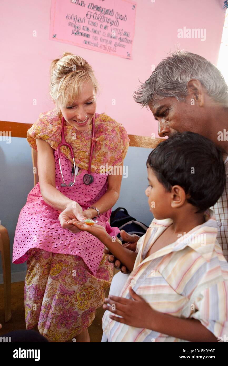 Una donna con uno stetoscopio dando un ragazzo di un trattamento dopo un check up; Sathyamangalam, Tamil Nadu, India Foto Stock