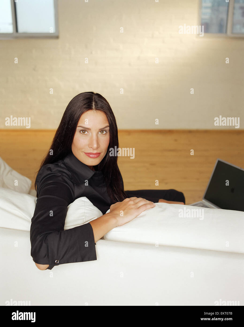 Fv5434, Peter Mintz; donna seduta sul divano bianco con il computer portatile Foto Stock