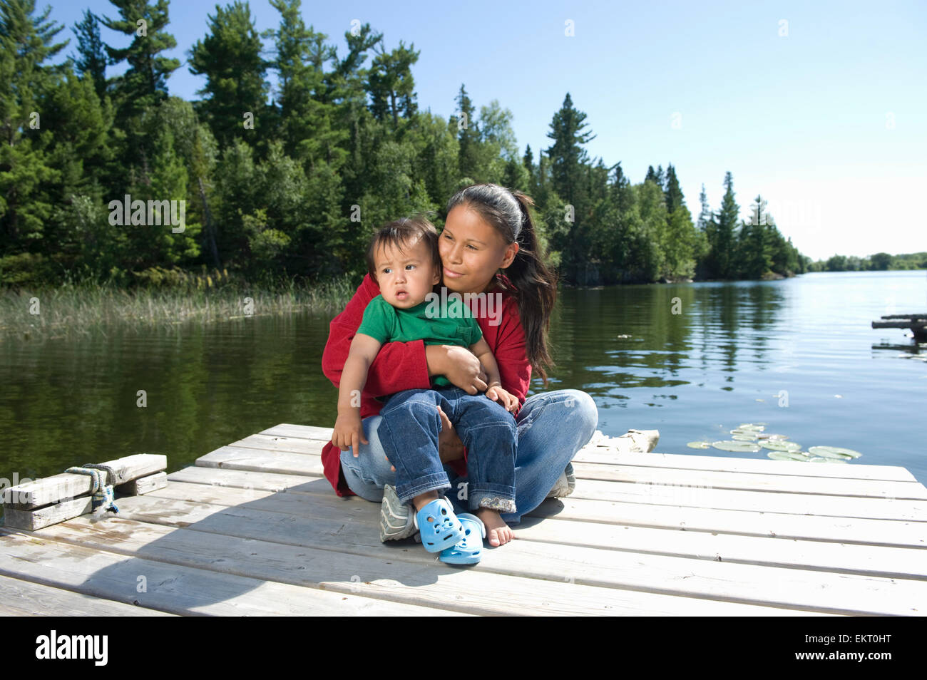 Nativo di Madre aborigena su un dock con suo figlio in Shoal Lake, Ontario, Canada. Foto Stock