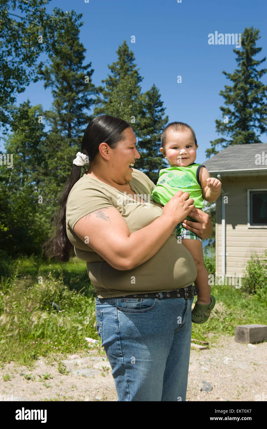 Native American madre con suo figlio in piedi al di fuori di fronte a una casa. Foto Stock