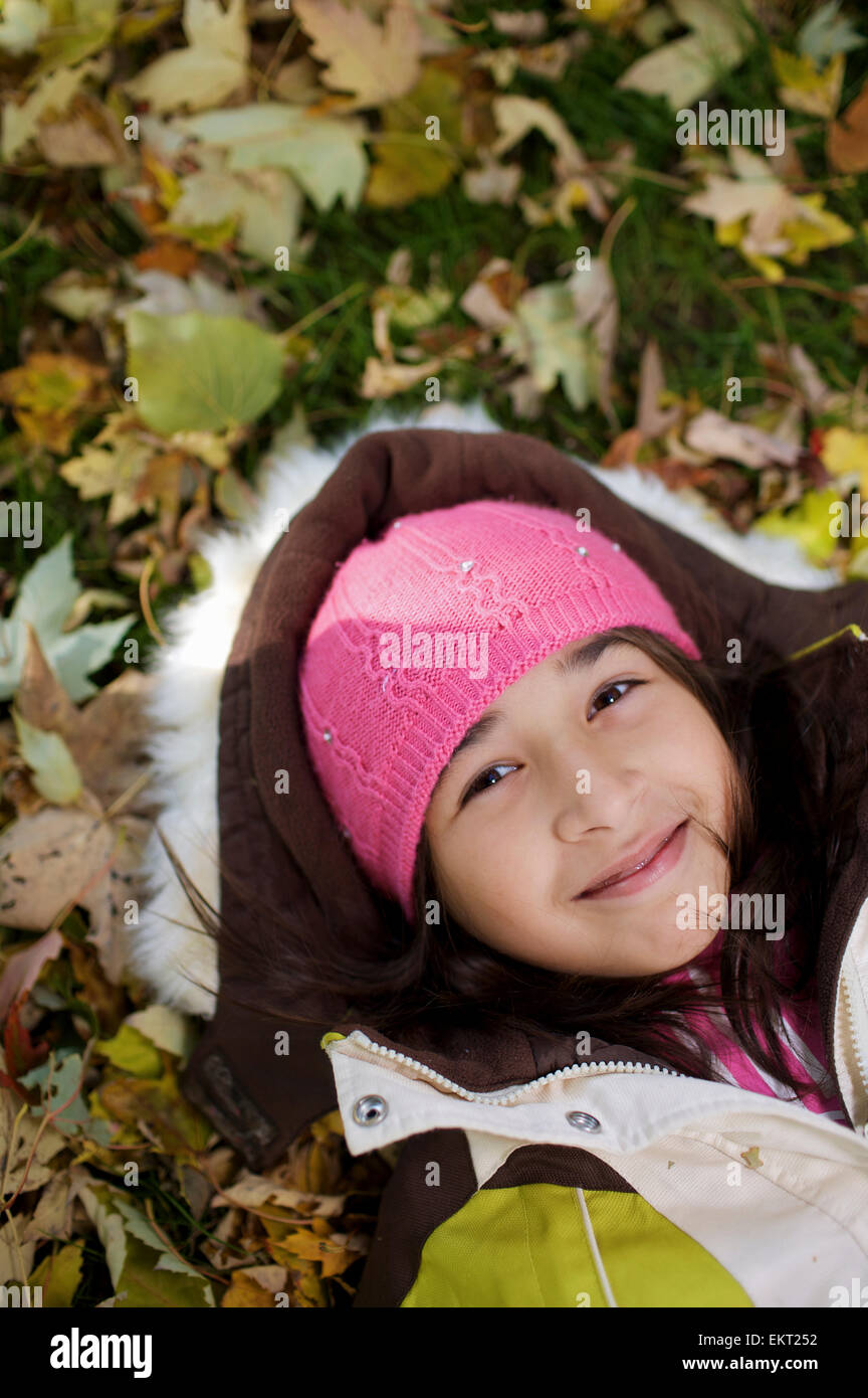 Medio Orientale ragazza distesa in foglie di autunno fuori scuola Esl; Guelph Ontario Canada Foto Stock