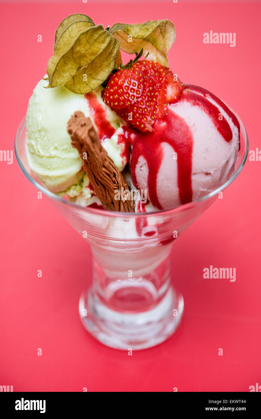 Una vaniglia e gelato alla fragola gelato, con una fragola e physalis sulla parte superiore e un scaglie di cioccolato. Foto Stock