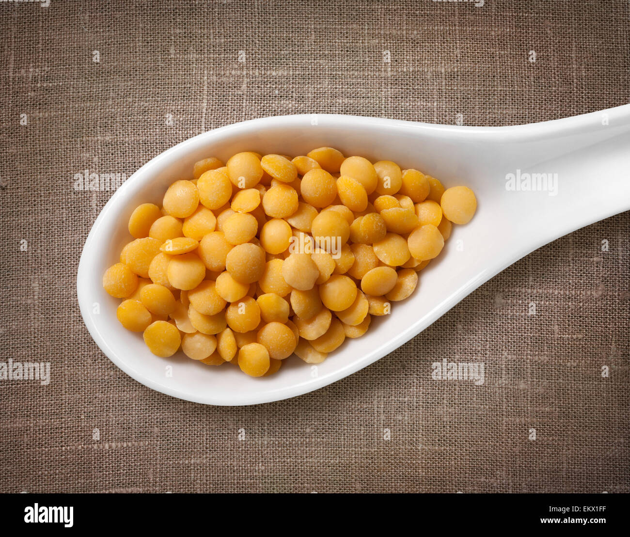 Lenticchia giallo in porcellana bianca cucchiaio / foto ad alta risoluzione di grano in porcellana bianca cucchiaio su tela cilicio sfondo Foto Stock