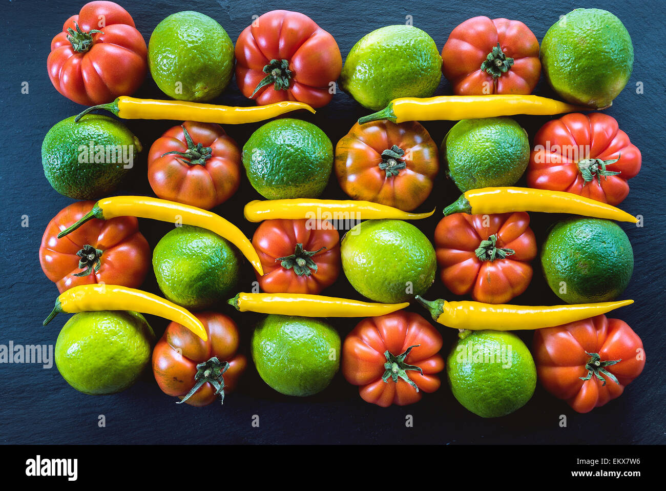 Ancora vita pomodoro Oxheart di pomodoro o di Bull in cuore di Lime peperoncino paprica su sfondo nero rosso verde giallo foof arte F Foto Stock