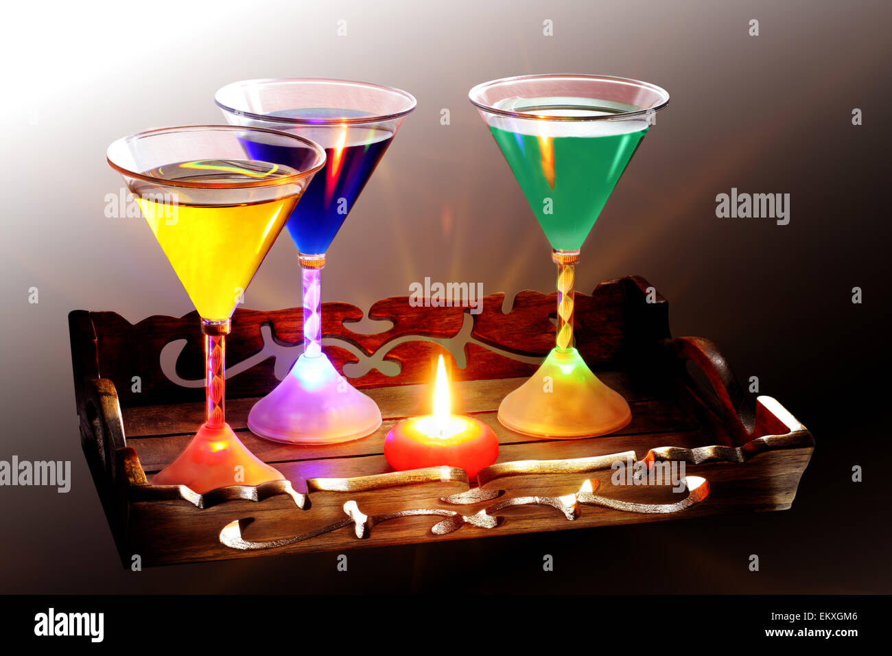 Un vassoio decorato intagliato che contiene una candela e tre bicchieri da cocktail, ogni vetro è illuminato dall'interno della base da luci a LED Foto Stock