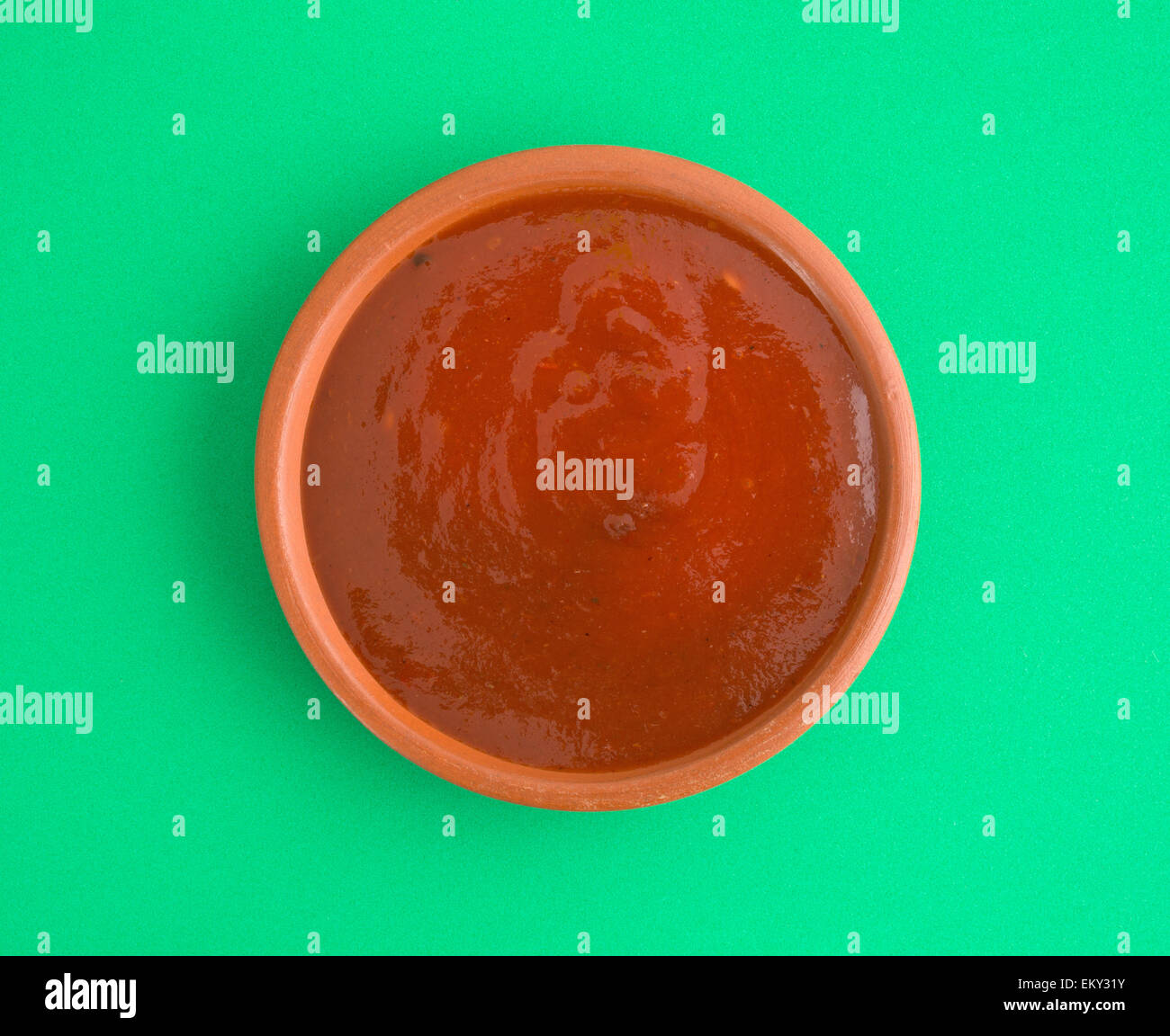 Vista dall'alto di una ciotola di salsa taco su uno sfondo verde. Foto Stock