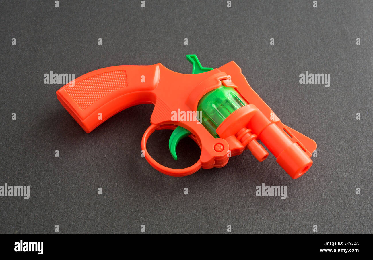 Un arancione e verde pistola giocattolo cap su uno sfondo nero. Foto Stock