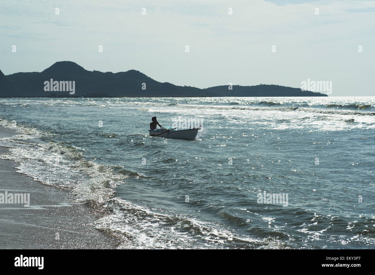 Un uomo su una barca a remi in spiaggia; Prachuap Thailandia Foto Stock