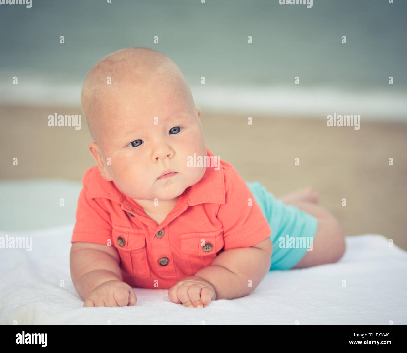 Carino il bambino posa sul lettino in spiaggia Foto Stock