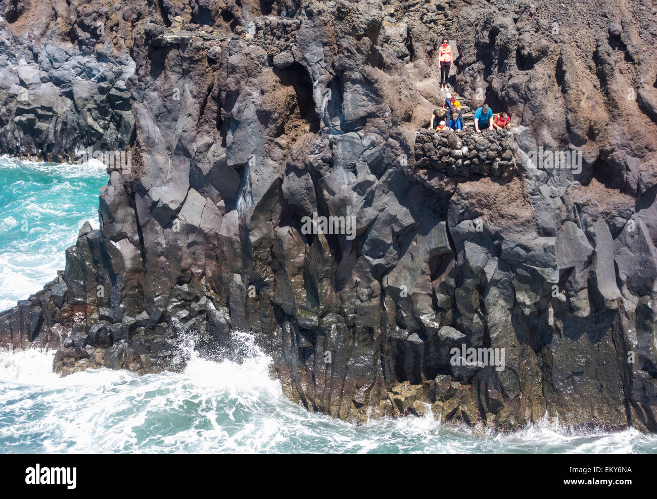 I turisti al punto di visualizzazione affacciato sul mare a Los Hervideros a Lanzarote, Isole Canarie, Spagna Foto Stock