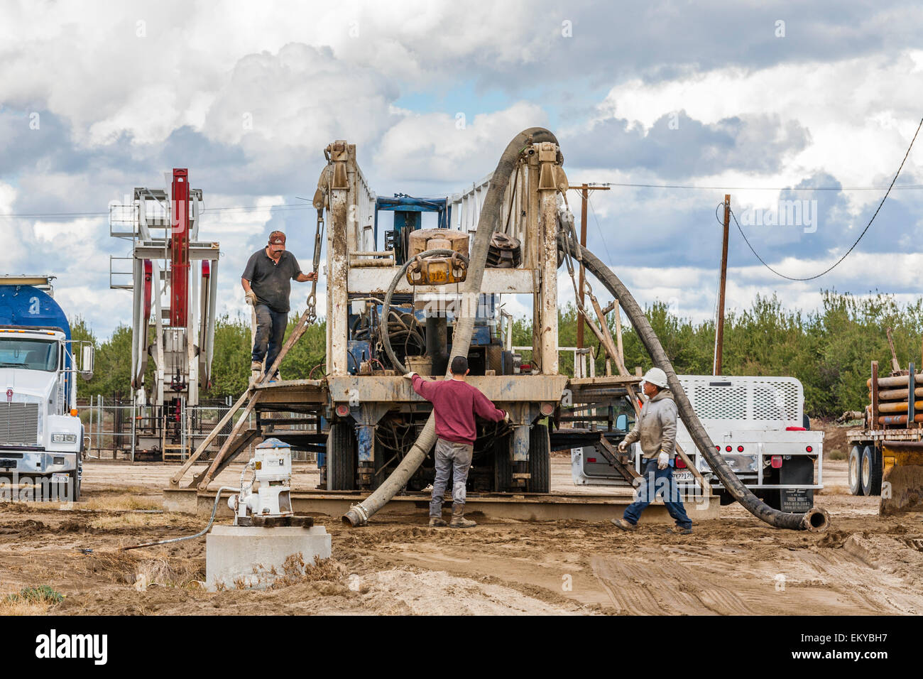 Pozzo di acqua essendo la perforazione accanto al pozzo petrolifero e fracking sito nella mandorla Orchard. Kern County, California Foto Stock
