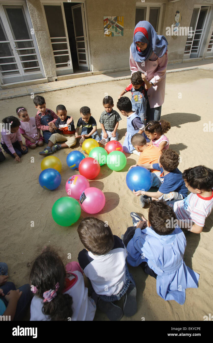 Un gruppo di bambini con il loro insegnante giocando in asilo nido; Alessandria, Egitto Foto Stock